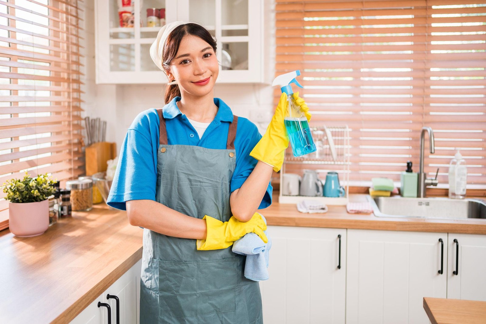 A Darati LLC professional cleaner with spray and microfiber cloth in a bright, spotless kitchen